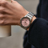 silver stainless steel watch with pink dial worn on wrist
