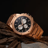 Rose gold watch with a black dial on a dark background