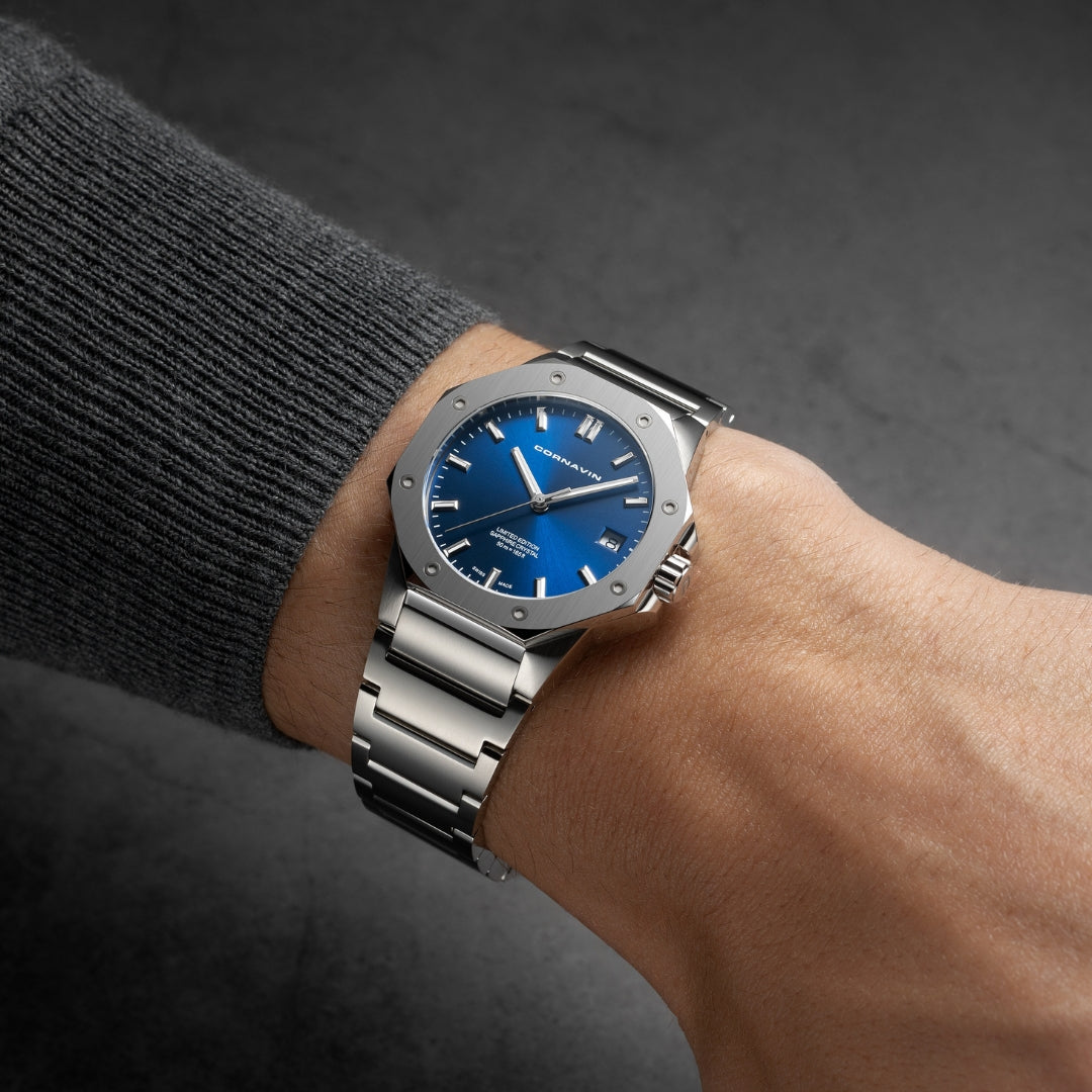 man wearing silver watch with blue dial and grey sweater